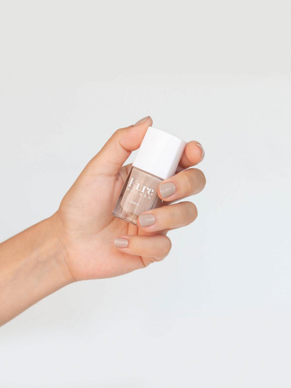 hand with painted nails holding a bottle of nail polish