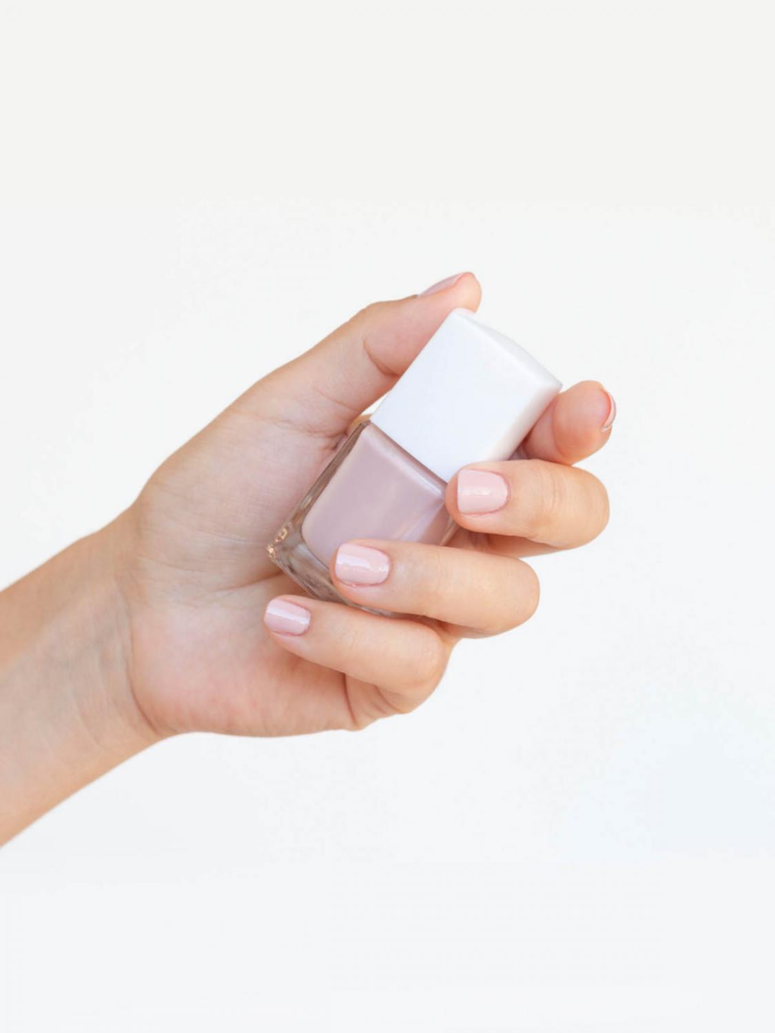 hand with painted nails holding a bottle of nail polish