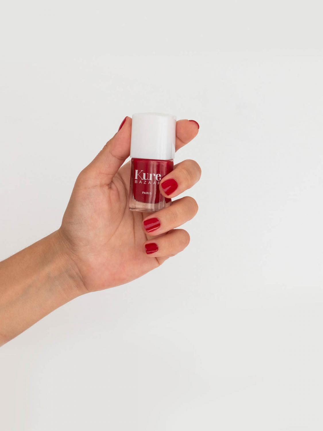 hand with painted nails holding a bottle of nail polish