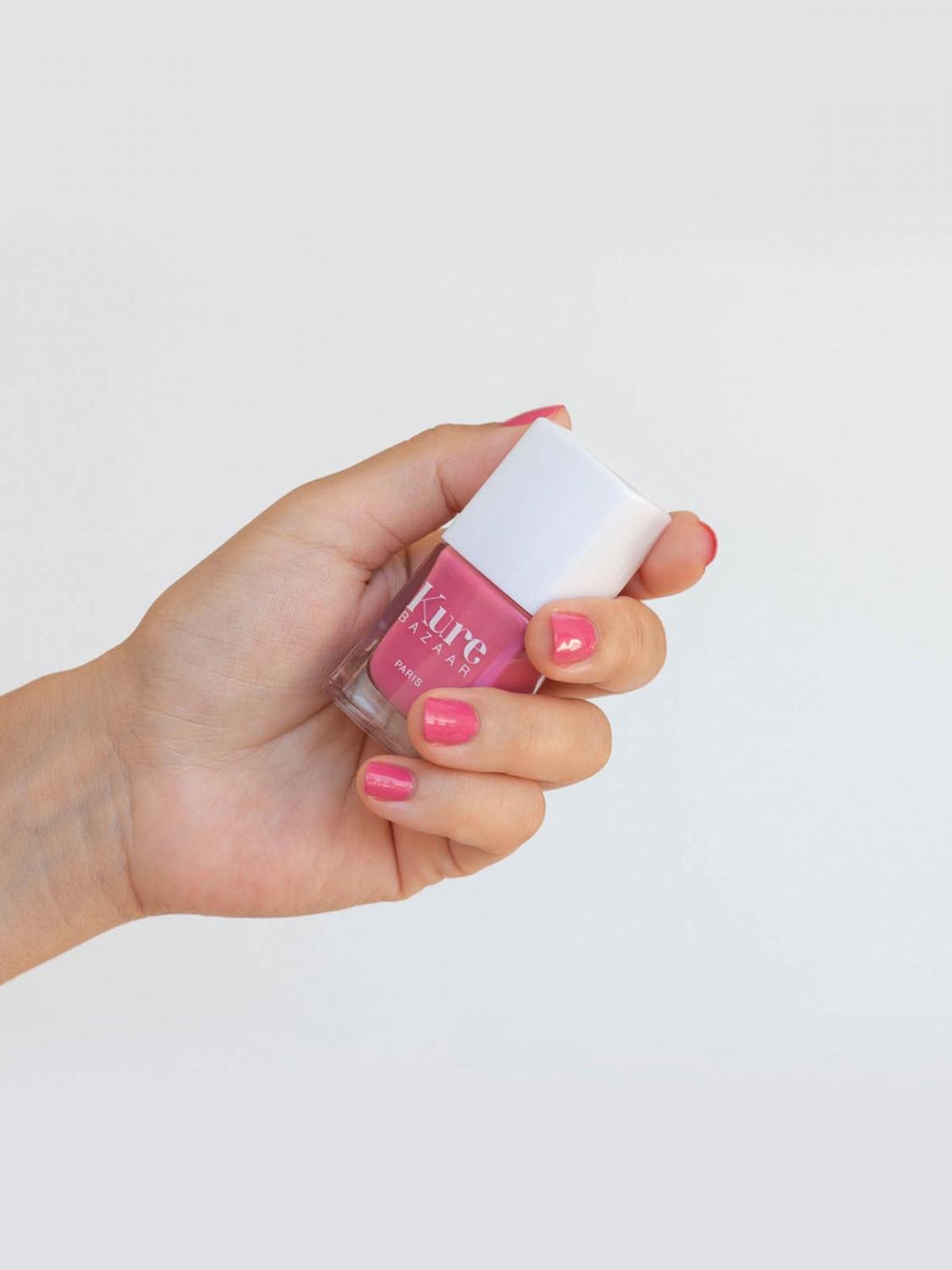 hand with painted nails holding a bottle of nail polish