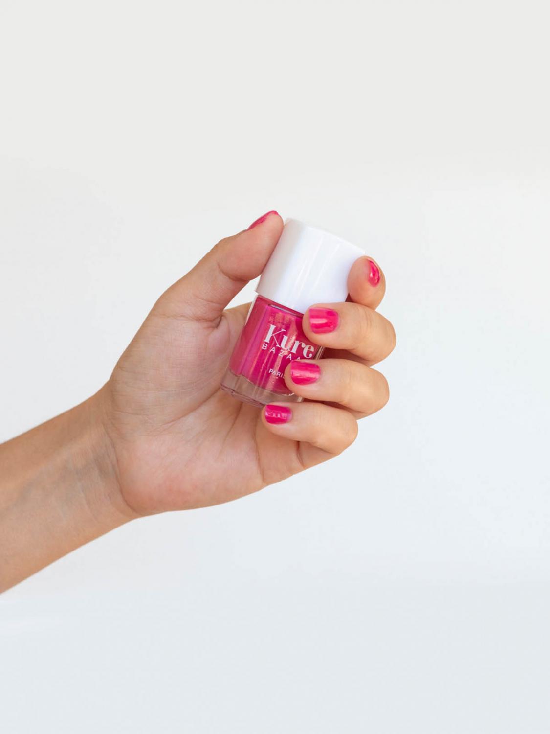 hand with painted nails holding a bottle of nail polish