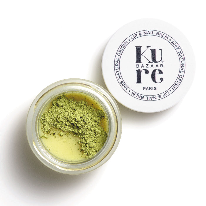 A jar of matcha shea butter nail balm by Kure Bazaar with some green matcha powder 