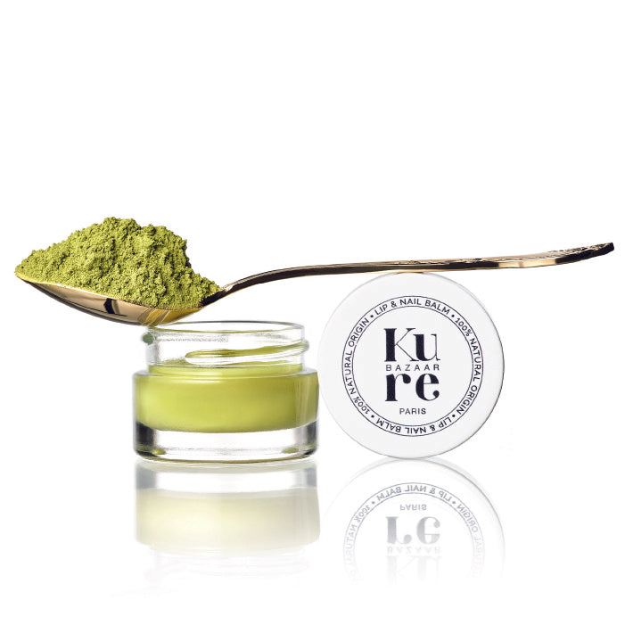 A jar of matcha shea butter nail balm by Kure Bazaar with a spoonful of green matcha powder