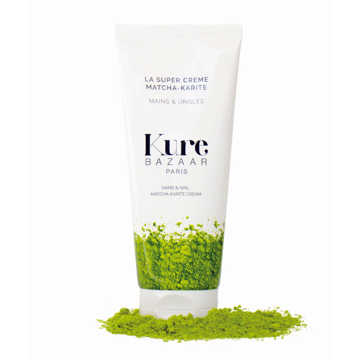 A bottle of matcha shea butter hand cream by Kure Bazaar on green matcha powder